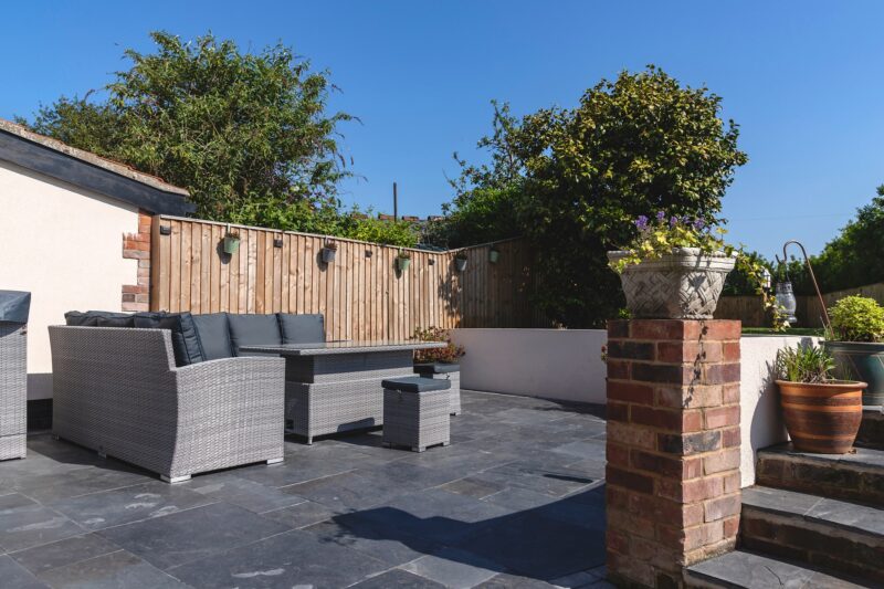 Slate patio with garden furniture and a brick pillar