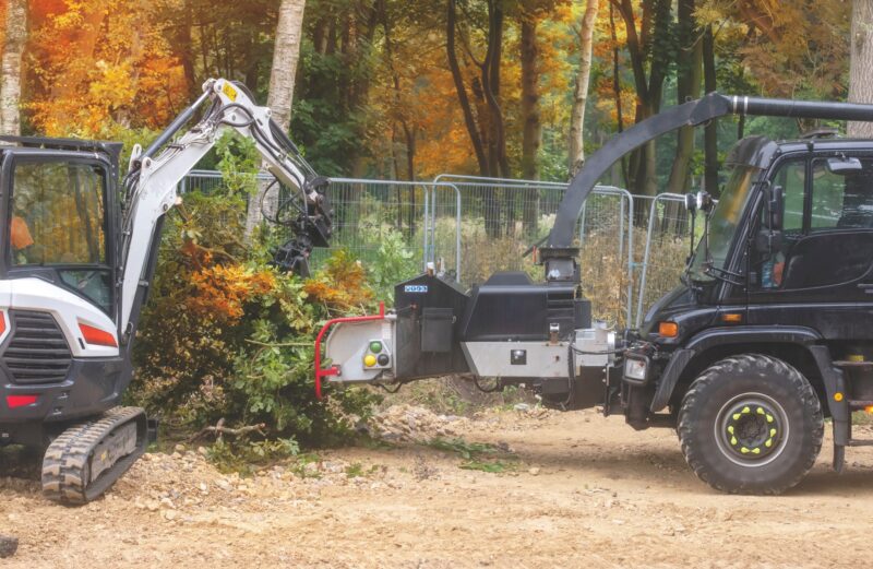 Excavator and wood chipper clearing trees in an autumn wood